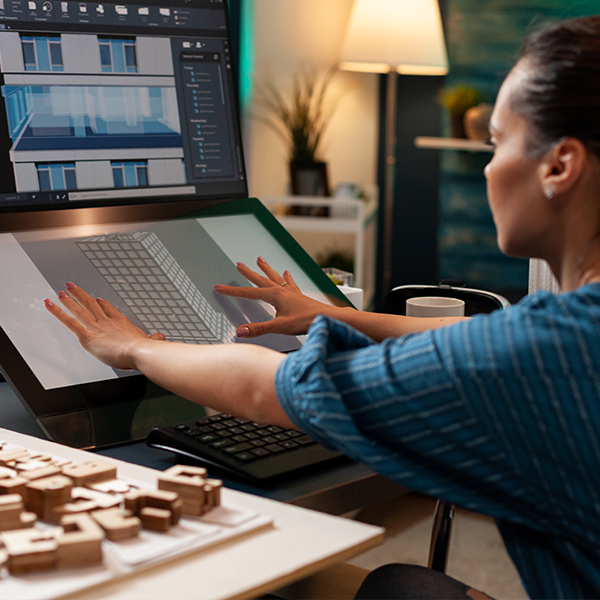 Mitarbeiterin arbeitet an einem 3D-Modellhaus am PC