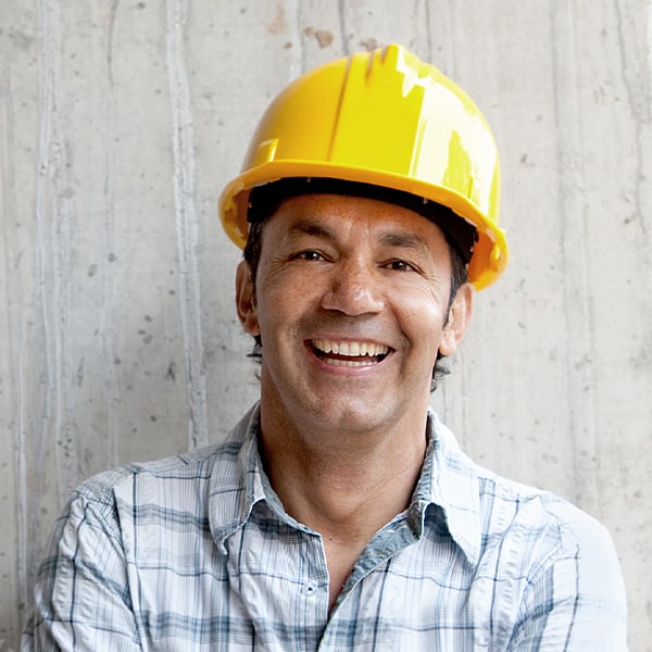 Mann mit Bauhelm, der in die Kamera lächelt