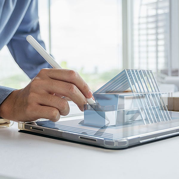 Ein Mann zeichnet einen Gebäudeumriss auf einem Tablet in 3D-Ansicht