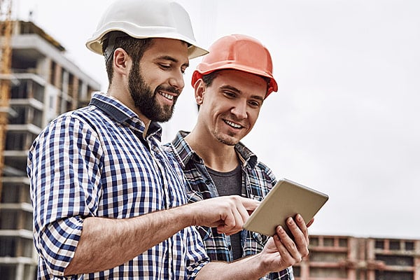 Zwei Bauarbeiter schauen auf ein Tablet