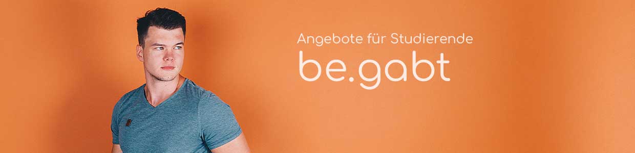 Mann steht vor Schriftzug be.gabt und orangenem Hintergrund Mann steht vor Schriftzug be.gabt und orangenem Hintergrund